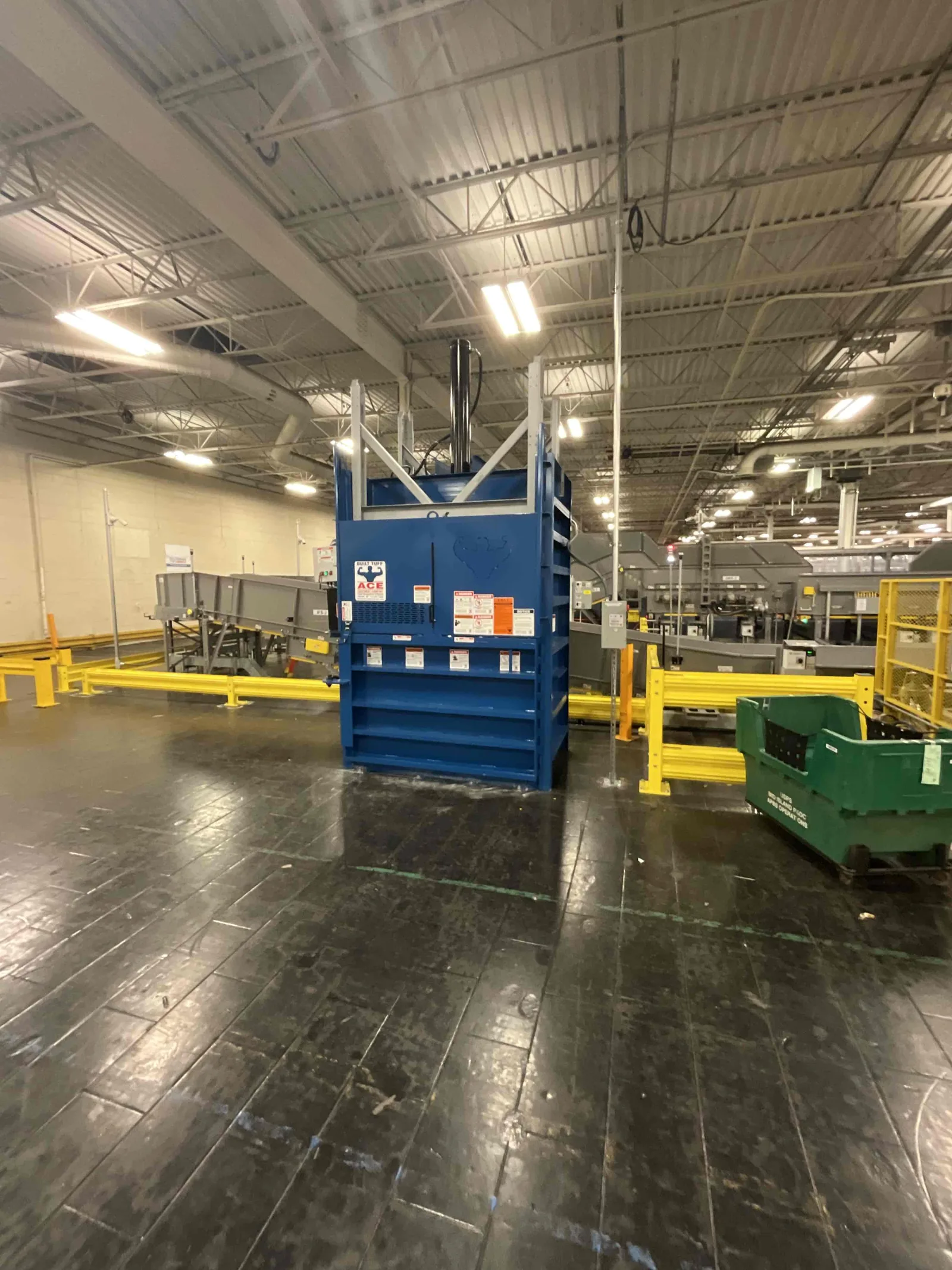 A blue vertical baler on a warehouse floor