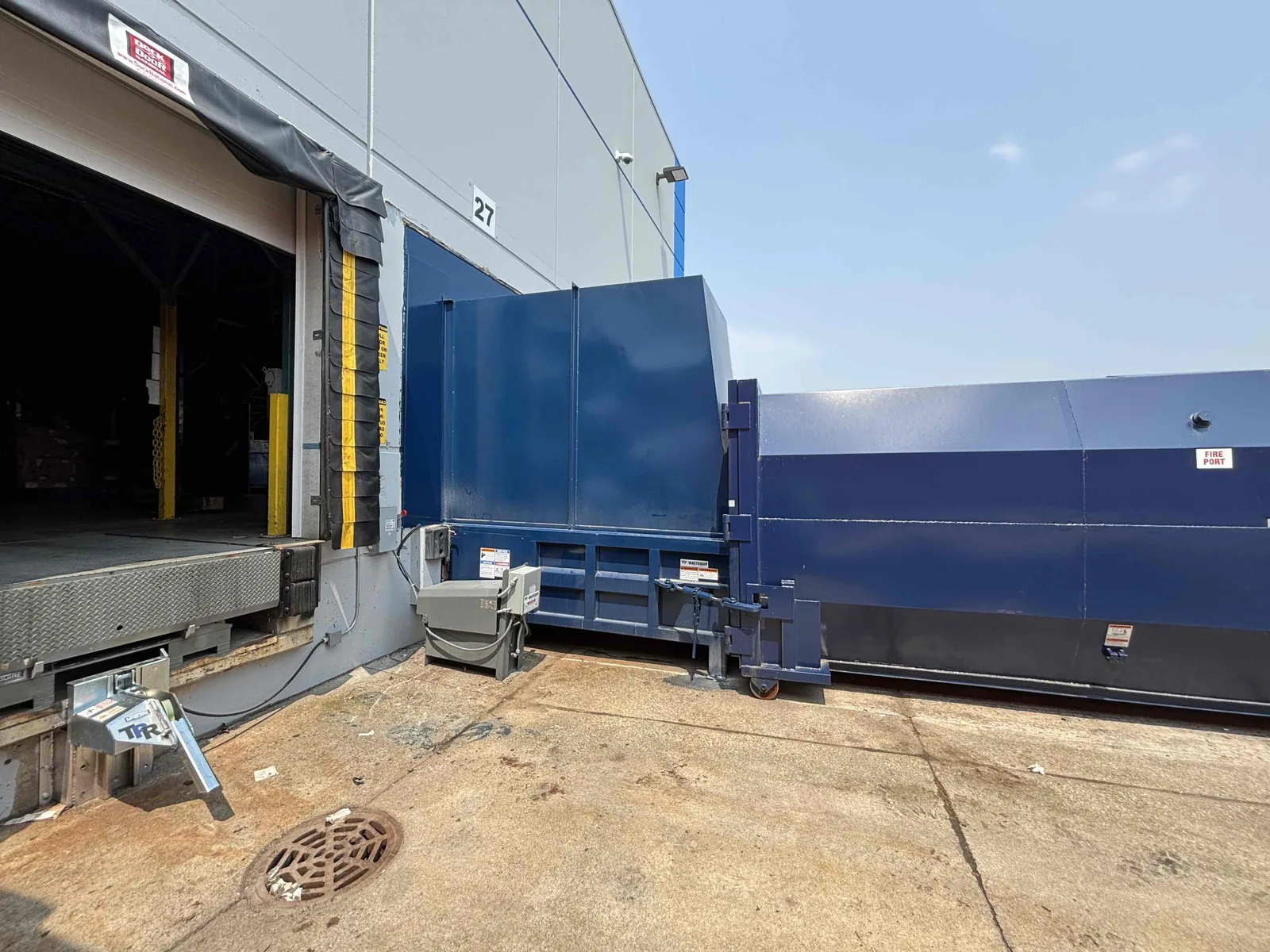 A blue compactor installed at a loading dock