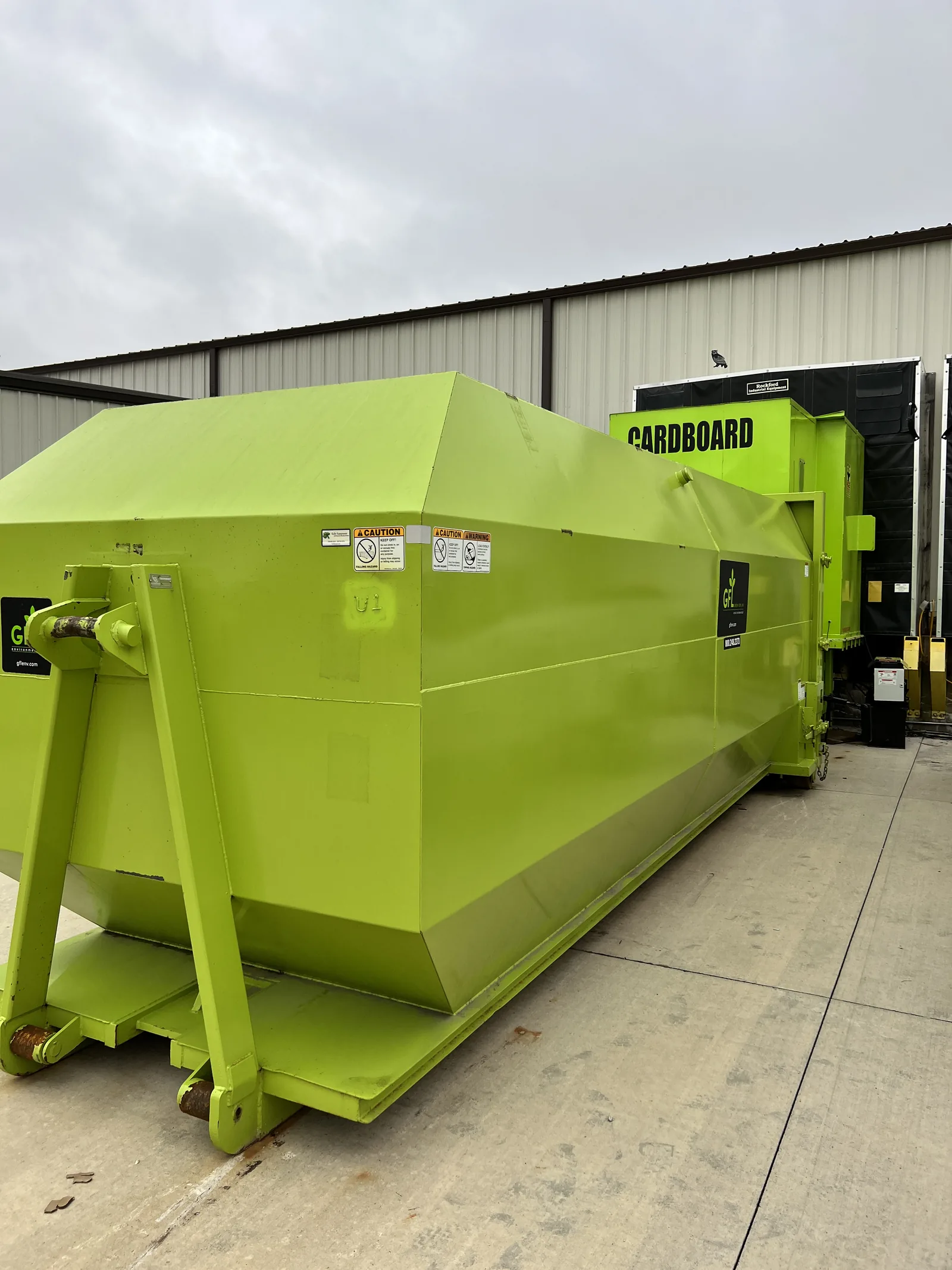 A lime green compactor installed against a building