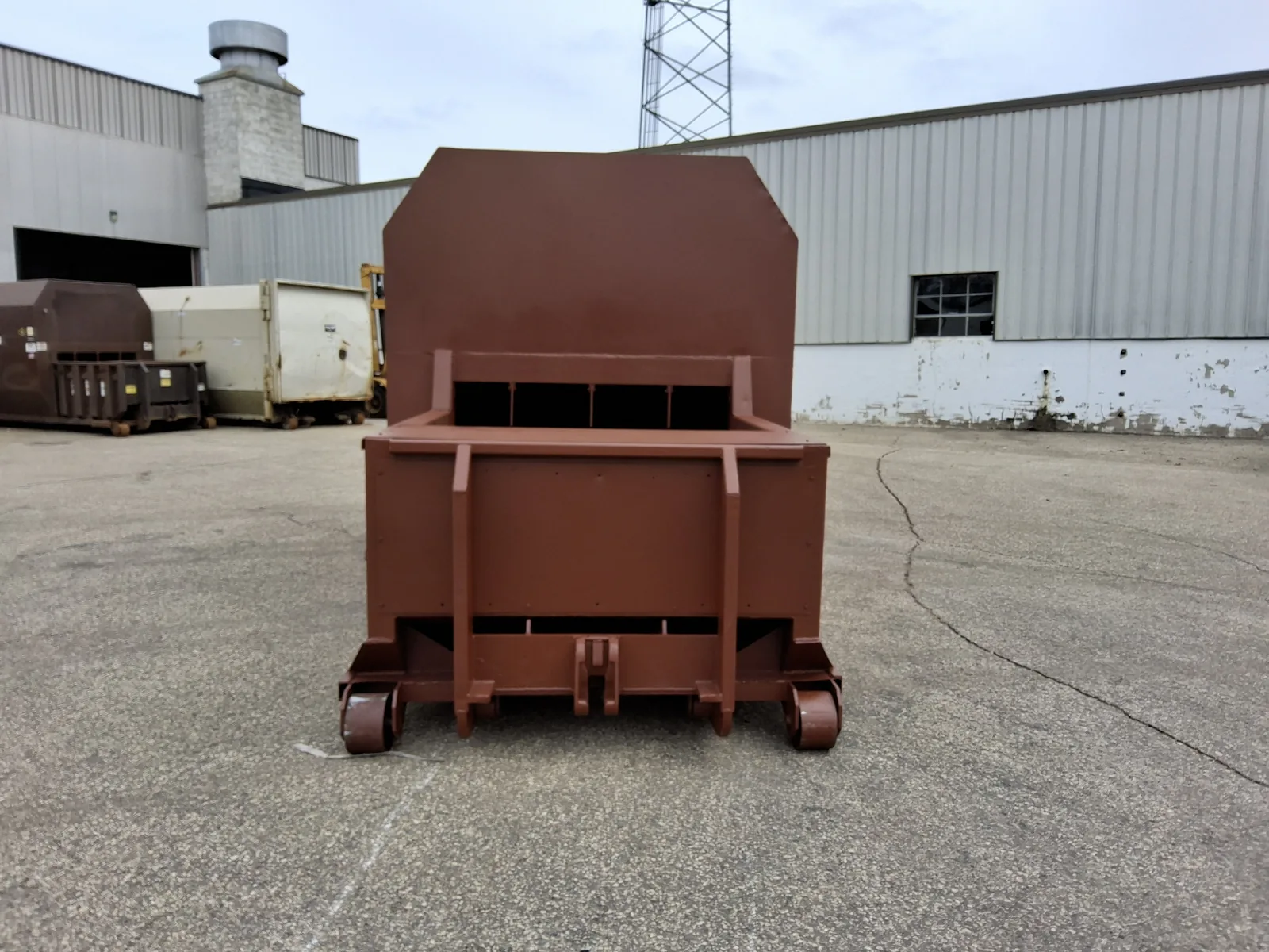 A brown roll-off container in the yard