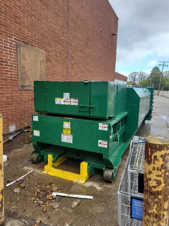 A green compactor container beside a loading dock