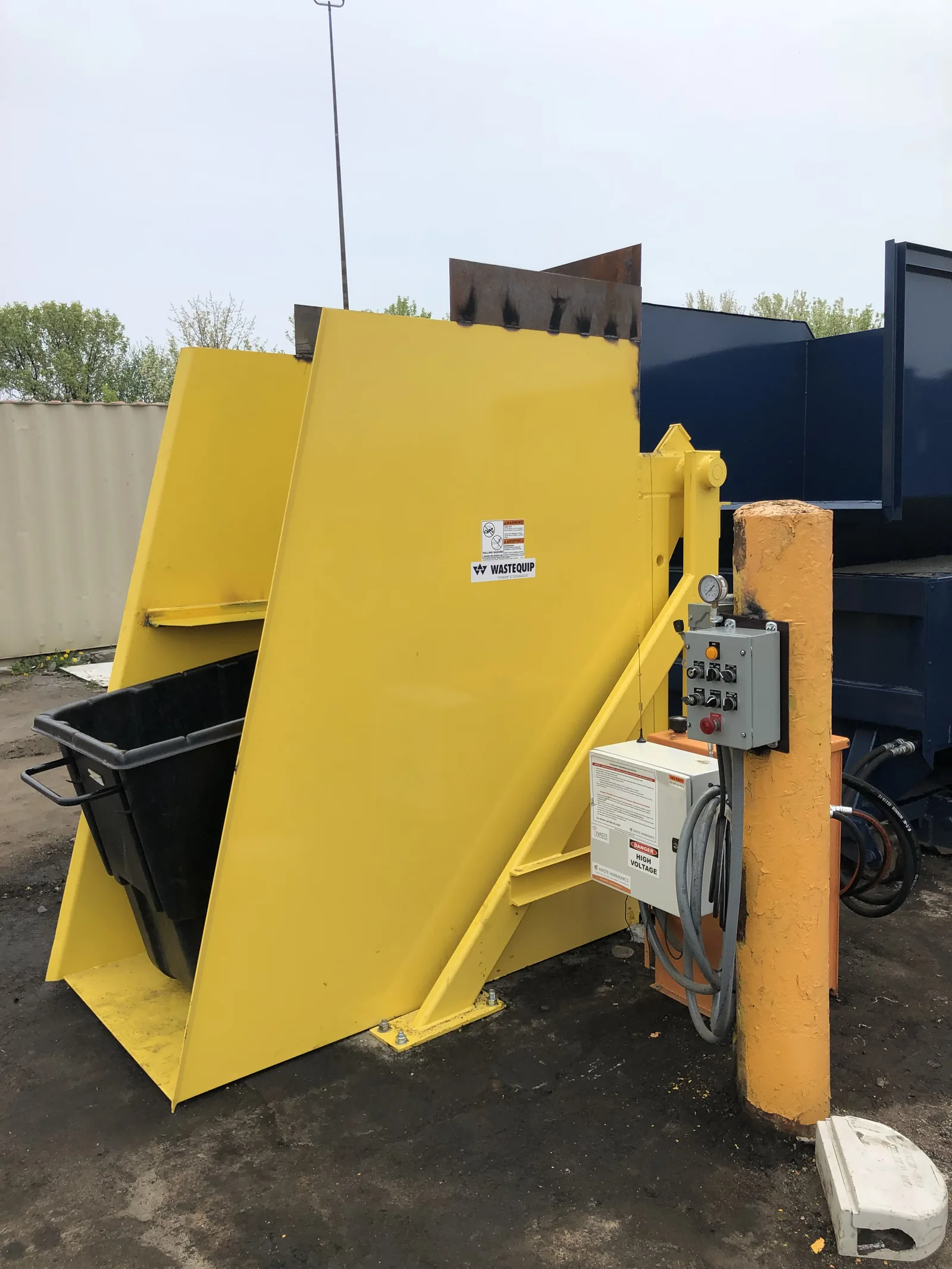 A yellow chute hopper feeding a compactor